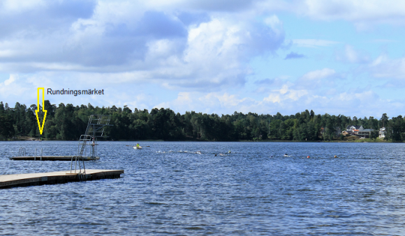 En följebåt finns med ute på vattnet för att hålla koll på simmarna. Långt därute till vänster i bild skymtar rundningsmärket.